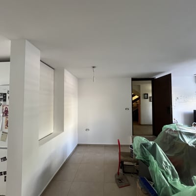 חדר עם קירות צבועים, כיסאות מכוסים בניילון, כלי עבודה לצביעה