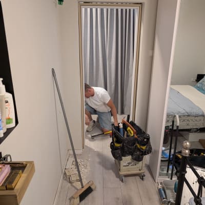 אדם עובד על משקוף דלת עם כלים שונים