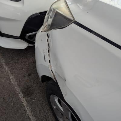 שני רכבים לבנים עם נזק לפגוש ולכנף