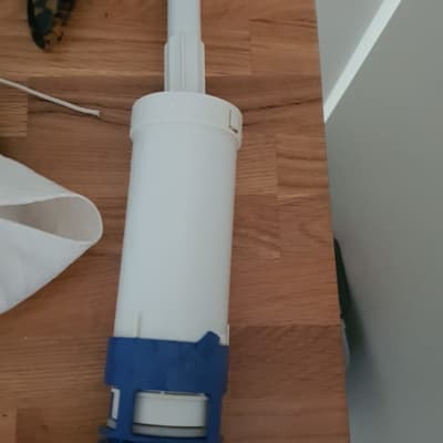 חלק פלסטיק לבן עם תפס כחול על שולחן עץ