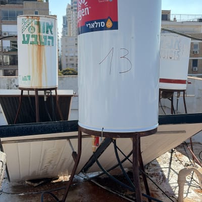 דודי שמש על גג בניין עם צנרת וחיבורים