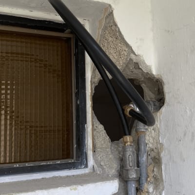 צינור שחור מחובר לקיר עם חלון קטן