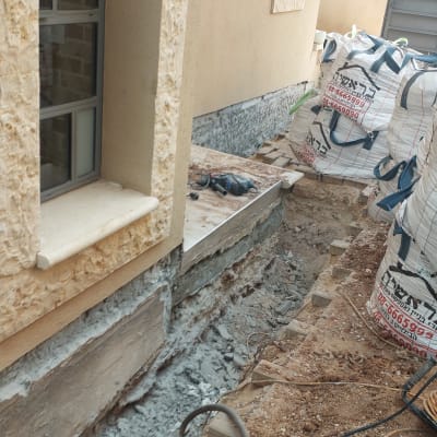 שקיות חומרי בנייה ליד קיר חיצוני עם עבודות איטום