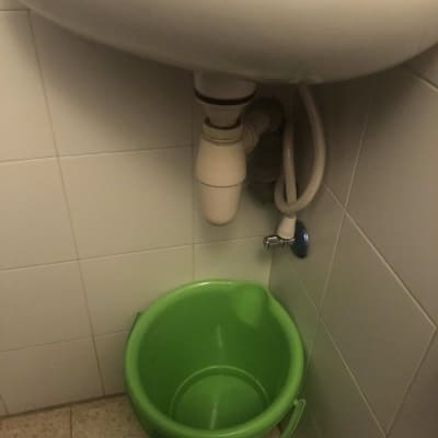 כיור עם דלי ירוק מתחת לצנרת