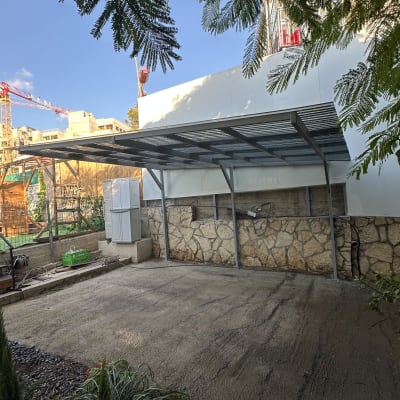 מבנה מתכת עם גג ליד קיר אבן