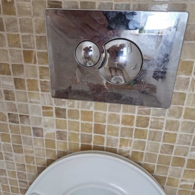 לחצן הדחה על קיר אריחים בשירותים