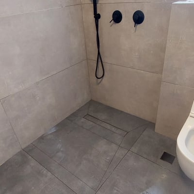 מקלחת עם אריחים אפורים, ראש מקלחת ומדף מתכת