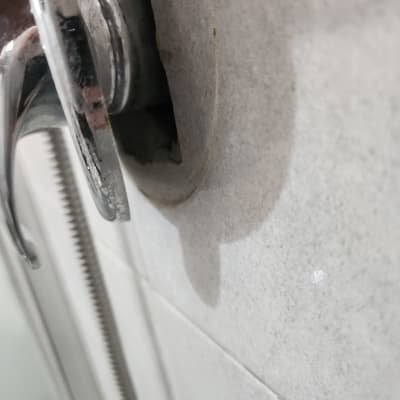 ברז מתכת עם חור בקיר מאחוריו