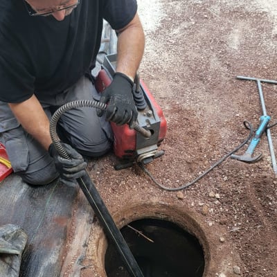 אדם עובד עם מכונת ניקוי צינורות בור ביוב