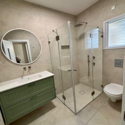 חדר אמבטיה משופץ עם מקלחון זכוכית וכיור ירוק