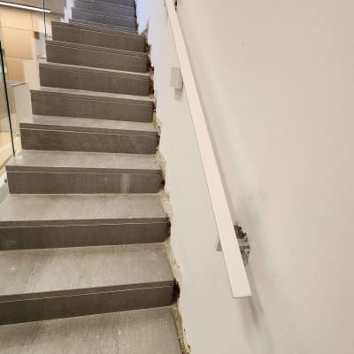 מעקה לבן לצד מדרגות אפורות עם קיר זכוכית