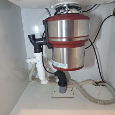 מתקן טוחן אשפה מתחת לכיור עם צינורות חיבור