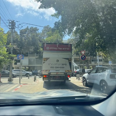 משאית הובלות ברחוב עם עצים ומכוניות