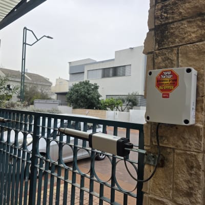 שער חשמלי עם מערכת בקרה מותקנת על עמוד אבן