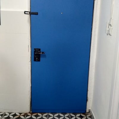 דלת כחולה עם ידית שחורה על רצפה מעוצבת