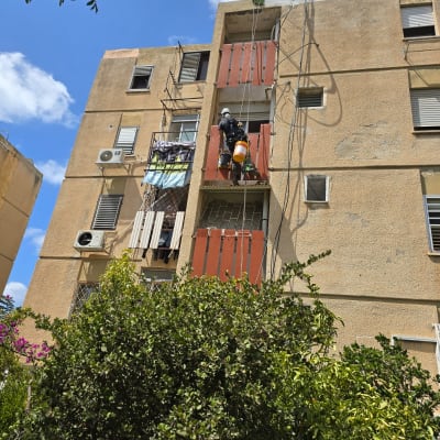 אדם עובד בגובה על בניין עם ציוד בטיחות