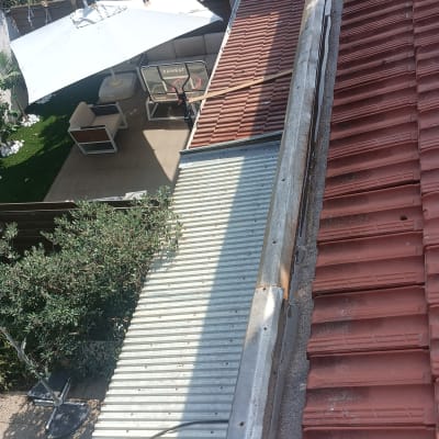 גג רעפים אדום וגג מתכת לבן בחצר בית