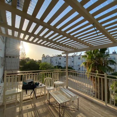 פרגולה מעץ על מרפסת עם שולחן וכיסאות