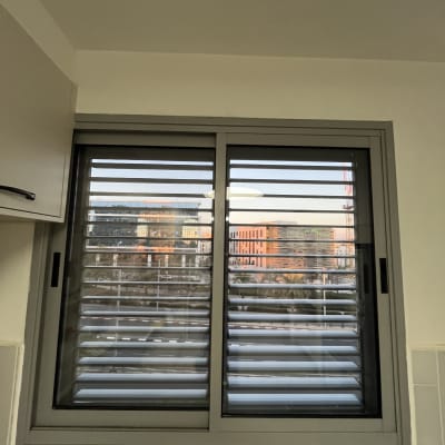 חלון עם תריסים נוף עירוני ברקע