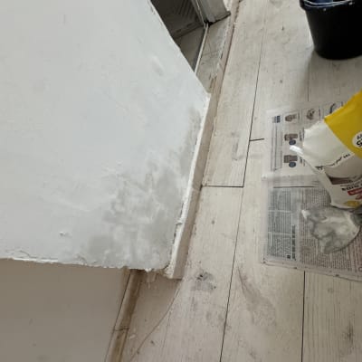 קיר צבוע עם כלי עבודה וחומרי צביעה על הרצפה