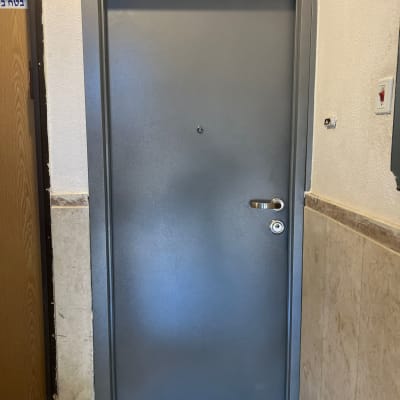 דלת מתכת אפורה עם ידית וכפתור נעילה