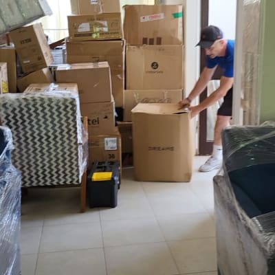 אדם מזיז קרטונים בחדר מלא ארגזים למעבר דירה