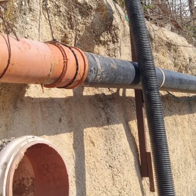 צינור שחור מחובר לקיר אבן עם צינור כתום