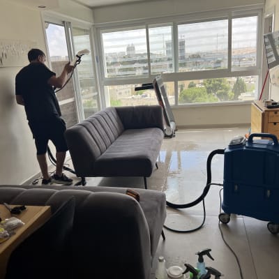 אדם מנקה ספה עם מכונת ניקוי מקצועית