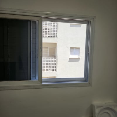 חלון אלומיניום עם מסגרת כסופה על קיר לבן