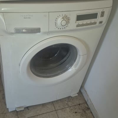 מכונת כביסה לבנה על רצפת אריחים
