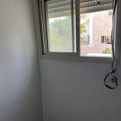 חלון עם תריסים פתוחים וקיר צבוע