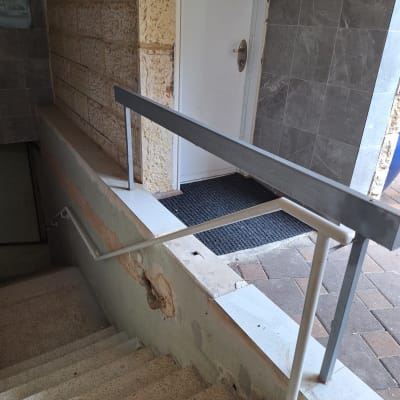 מעקה מתכת ליד מדרגות ודלת כניסה
