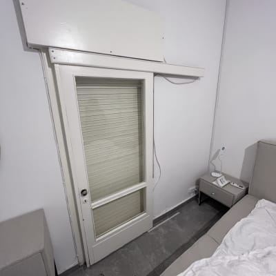 תריסים סגורים על דלת זכוכית לבנה בחדר שינה