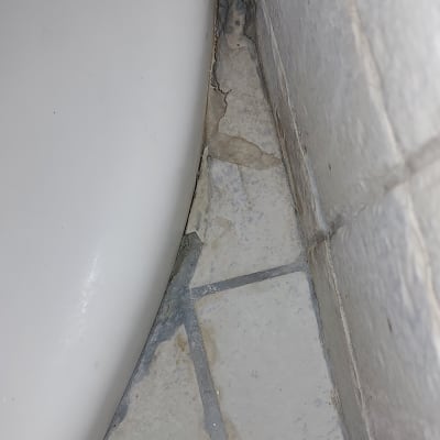 רצפה עם אריחים שבורים ליד קיר ואמבטיה