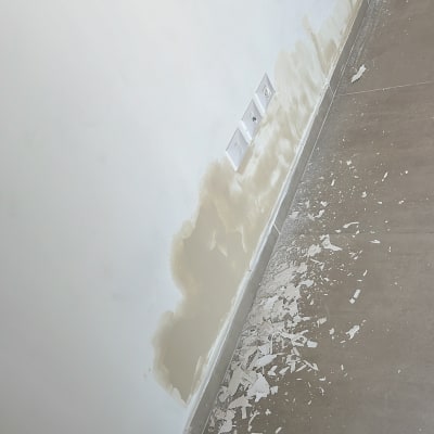 קיר עם תיקוני טיח ושברי טיח על הרצפה