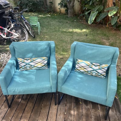 שני כיסאות כחולים עם כריות על דק עץ בגינה