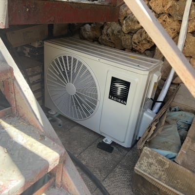 יחידת מזגן מותקנת מתחת למדרגות ליד קיר אבן