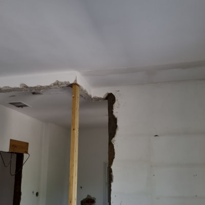 קיר שבור עם עמוד עץ זמני ותקרה חשופה