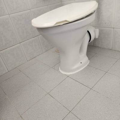 אסלה לבנה עם מכסה סגור וצינור מים מחובר