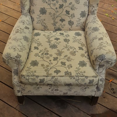 כורסה עם דוגמת פרחים וצינור ניקוי על רצפת עץ