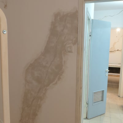 קיר עם תיקוני צבע וסדקים ליד דלת פתוחה