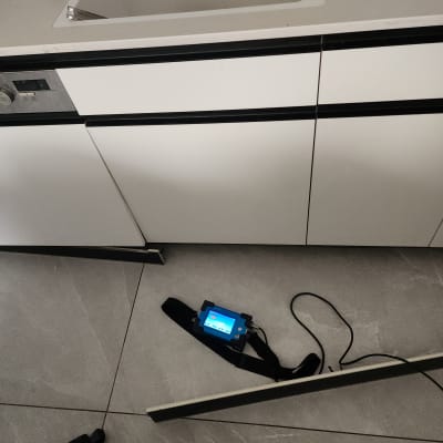 מכשיר דיגיטלי על הרצפה ליד ארון מטבח