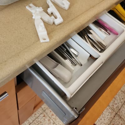 מגירת מטבח פתוחה עם סכו"ם וחלקי פלסטיק על השיש