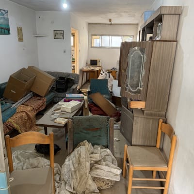 חדר מבולגן עם רהיטים וקרטונים, לפני פינוי