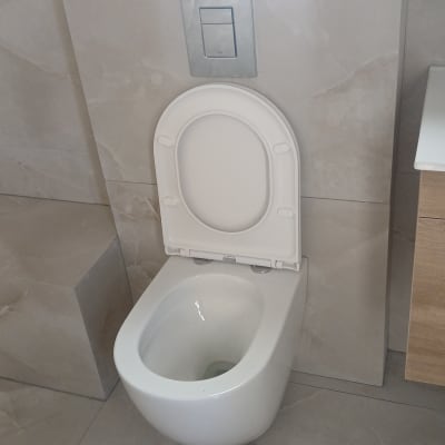 אסלה מותקנת בחדר אמבטיה עם אריחים אפורים