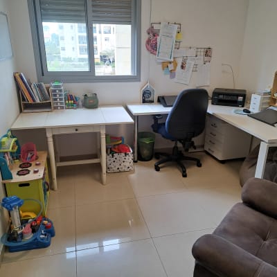 חדר עבודה מאורגן עם שולחנות, כיסא ומדפים