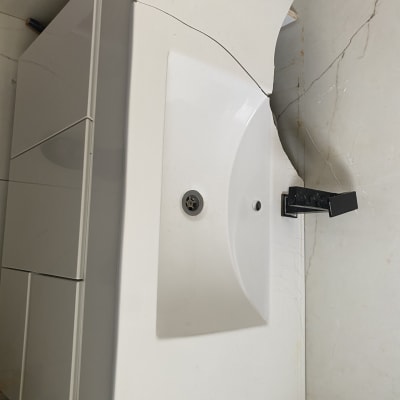 כיור שבור עם ברז שחור על ארון לבן