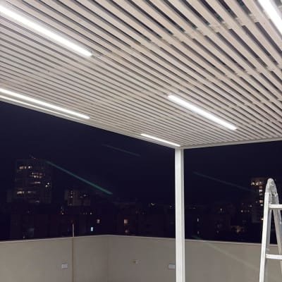 פרגולה מעץ עם תאורה על גג בלילה