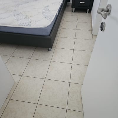 חדר שינה עם מיטה ומזרן על רצפת אריחים