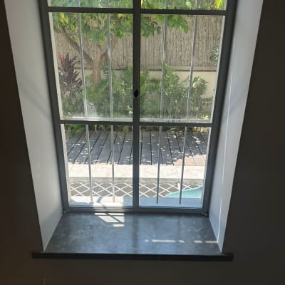 חלון עם סורגי מתכת ונוף גינה בחוץ